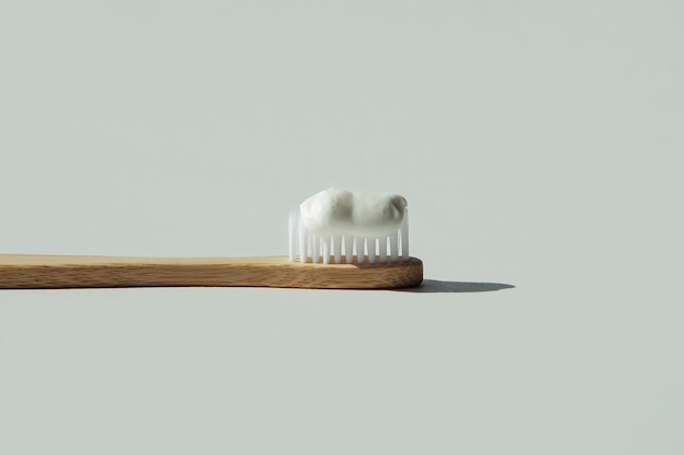 Cepillo de dientes de bambú natural con pasta de dientes sobre un fondo gris Espacio de copia de cepillo de dientes ecológico de madera