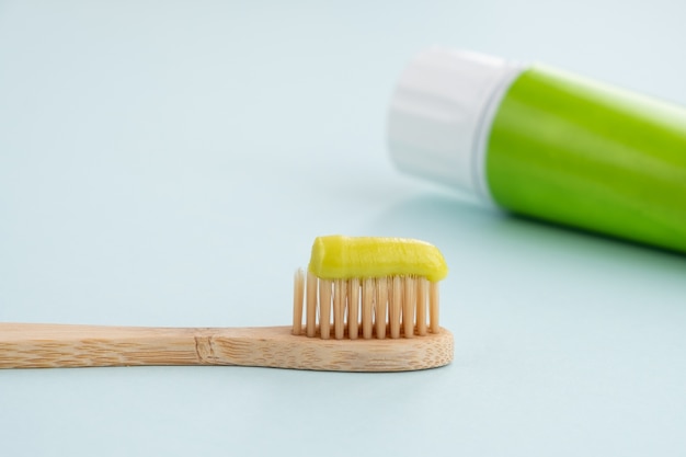 Cepillo de dientes de bambú con pasta de dientes verde en la mesa