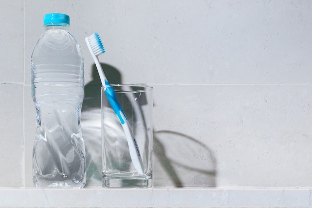 Cepillo de dientes blanco limpio con borde azul en vaso transparente