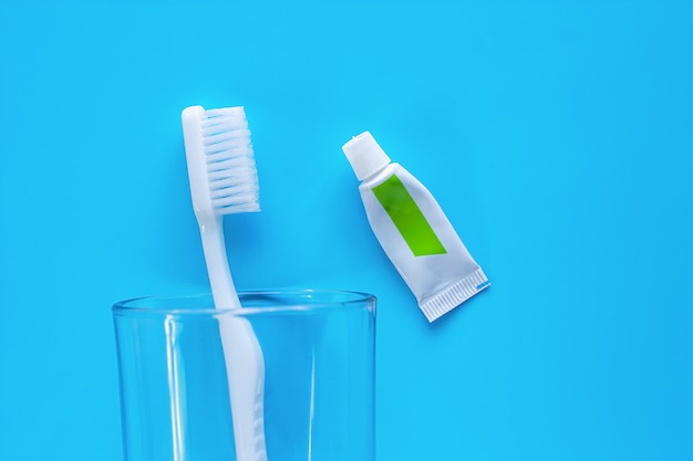 Foto cepillo de dientes blanco en el vidrio transparente con crema dental utilizada para limpiar los dientes sobre fondo azul