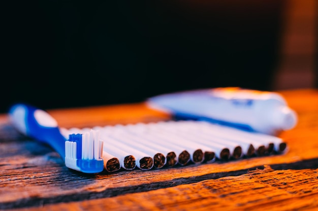 Cepillo de dientes y cigarrillos en la mesa de madera sobre fondo negro