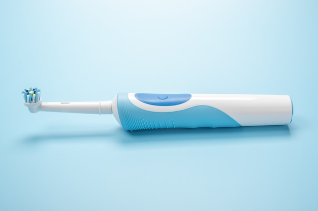 Cepillo de dientes eléctrico moderno se encuentra sobre fondo azul. Cepillo de dientes eléctrico recargable. cuidado bucal profesional y dientes sanos mediante el uso de un cepillo de dientes inteligente ultrasónico.