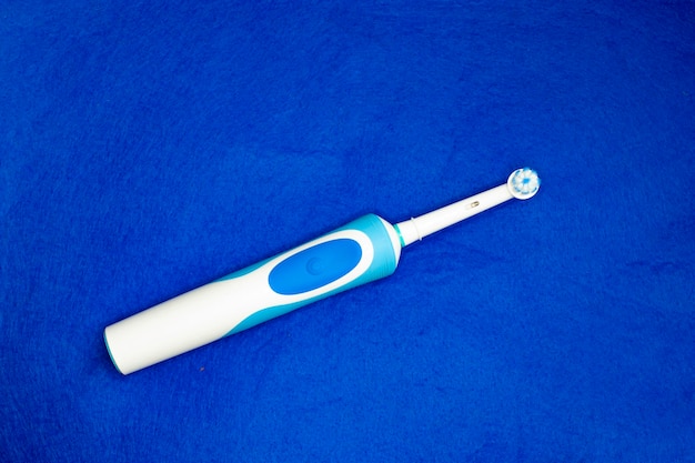 Cepillo de dientes eléctrico moderno de pie sobre un fondo azul Herramienta controlada para el cuidado oral diario