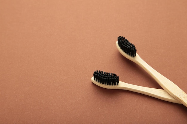 Cepillo de dientes de madera de bambú con cerdas de cepillo negro sobre fondo marrón.