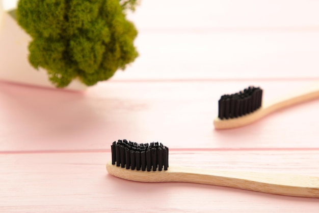Cepillo de dientes de madera de bambú con cerdas de cepillo negro sobre fondo rosa