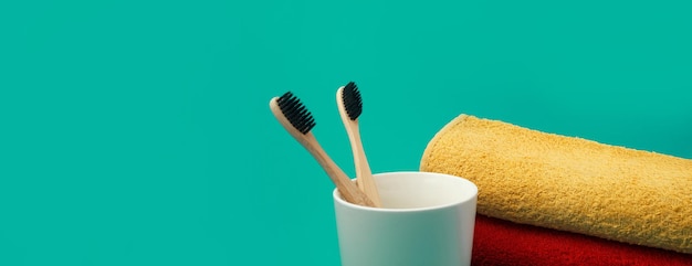 Cepillo de dientes de madera con toalla sobre fondo panorámico verde