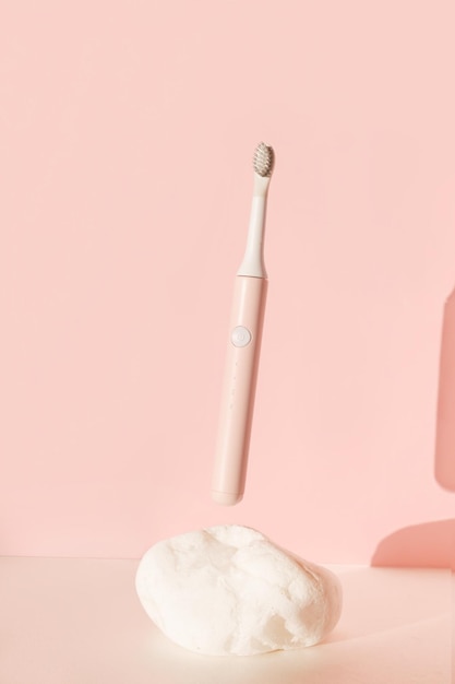 Cepillo de dientes ultrasónico moderno volador suministros para el cuidado dental en piedra blanca sobre fondo rosa pastel o...