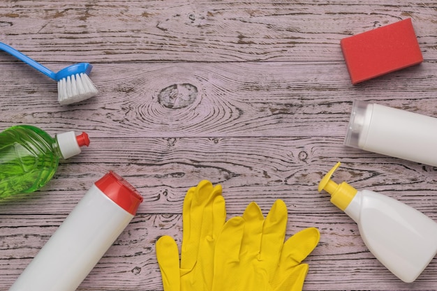 Cepillo guantes esponja y productos de limpieza sobre un fondo de madera Un lugar para su texto Kit de limpieza