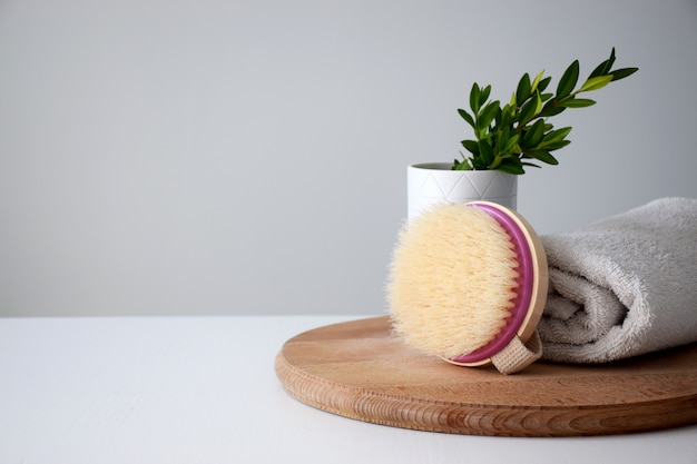 Foto cepillo de madera ecológica, recipiente con planta y toalla blanca sobre tabla redonda de madera