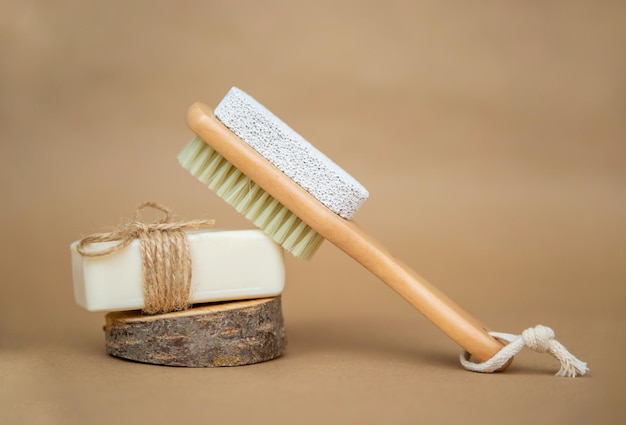 Cepillo de madera para masaje corporal seco y jabón natural Cepillo para pies y piedra pómez para tacones sobre fondo beige