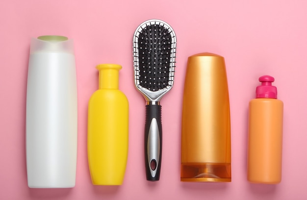 Cepillo de pelo con botellas de champú en rosa pastel. Cuidado del cabello. Higiene