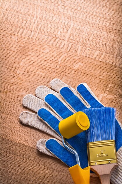 Cepillo de rodillo de pintura con guantes protectores en concepto de mantenimiento de tablero de madera