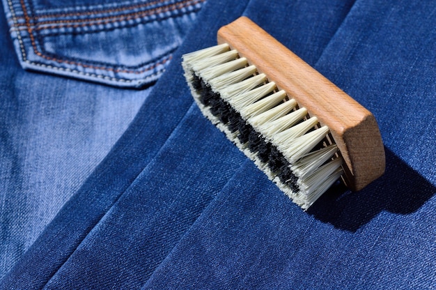 Un cepillo de ropa se encuentra sobre jeans doblados.