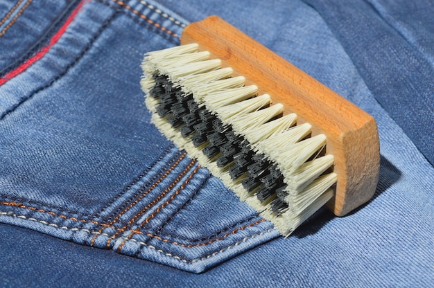 Un cepillo de ropa se encuentra sobre jeans doblados.