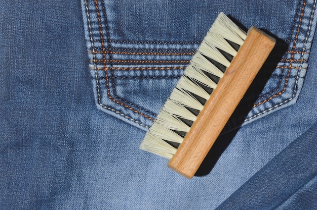 Un cepillo de ropa se encuentra sobre jeans doblados.