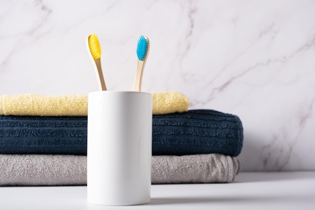 Cepillos de bambú con cerdas amarillas y azules en un vaso blanco