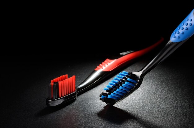 Cepillos de dientes azul y rojo sobre una superficie de grano negro