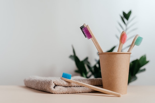 Cepillos de dientes de bambú ecológicos de diferentes colores en vaso de papel, concepto de desperdicio cero, estilo de vida sostenible