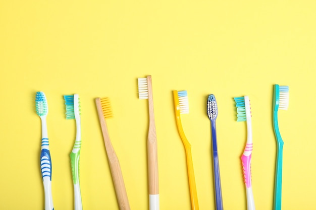 Cepillos de dientes de bambú natural y plástico en una vista superior de fondo de color