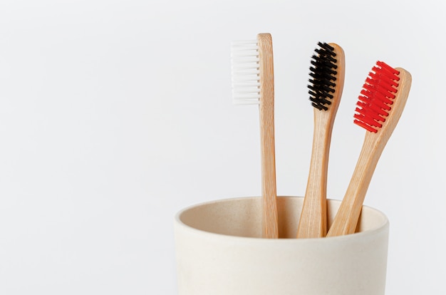 Cepillos de dientes de bambú rojo, blanco y negro en eco cup en blanco