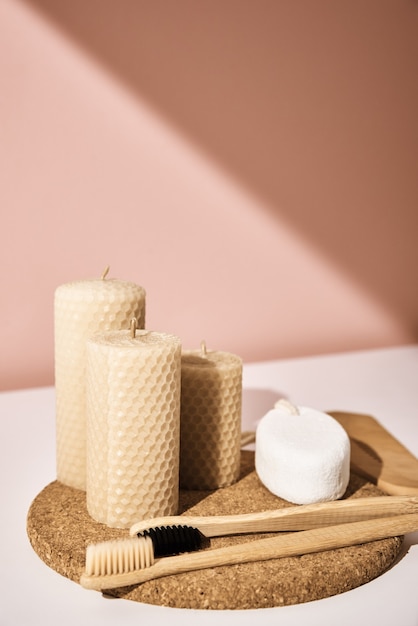 Cepillos de dientes de bambú y velas sobre fondo rosa. Reutilizar productos naturales