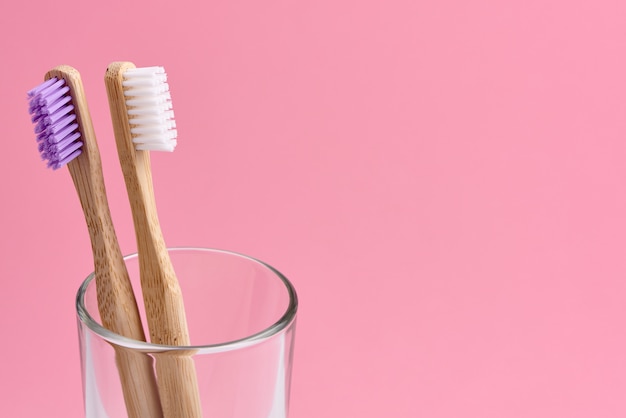 cepillos de dientes de bambú en vidrio sobre fondo rosa