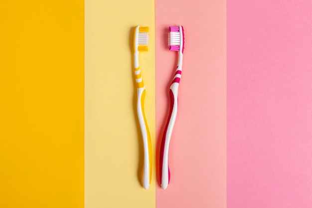 Foto cepillos de dientes en dos colores, amarillo y rosa, fondo de 2 colores.