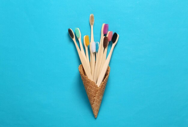 Cepillos de dientes ecológicos en un cono de galleta sobre un fondo azul Diseño creativo de cuidado dental