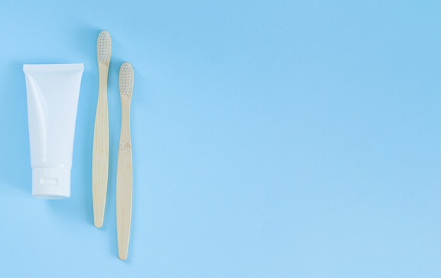 Cepillos de dientes de madera y vista superior de pasta de dientes sobre fondo azul.