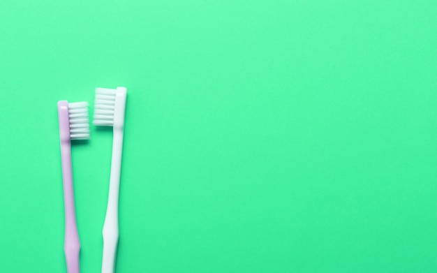 Cepillos de dientes rosados y blancos en la pared verde.