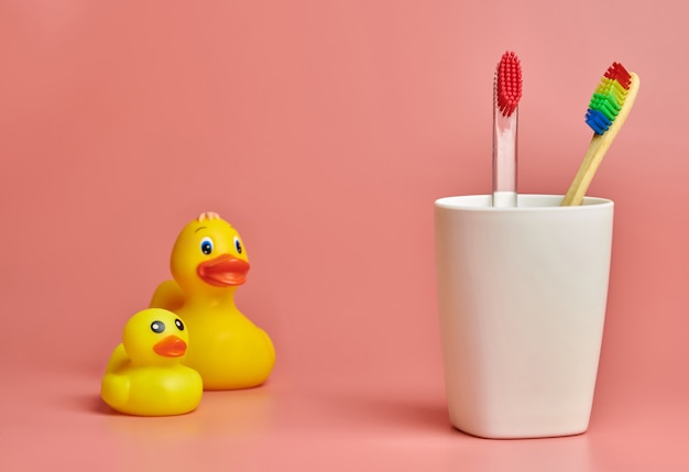 Cepillos de dientes en vaso de plástico y juguete de pato