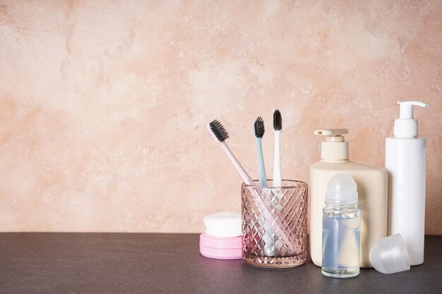 Cepillos de dientes en un vaso y productos de higiene de baño en beige