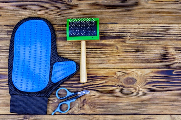 Cepillos para mascotas y cortadora de garras sobre un fondo de madera. Vista superior