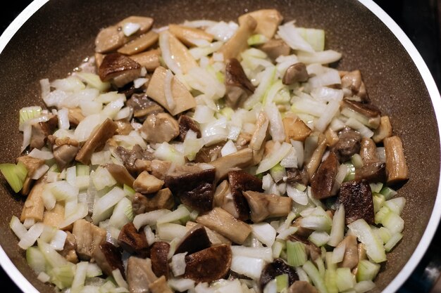 Ceps recém-colhidos com boletos de tampa marrom fritos em uma panela Cebola frita caseira e cogumelos na panela