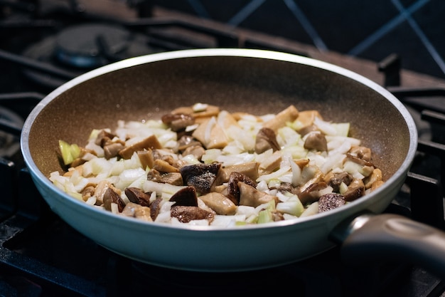 Ceps recién recolectados con boletus de tapa marrón fritos en una sartén Cebolla frita casera y champiñones en una sartén