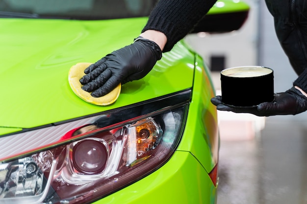 Cera dura para la protección de la pintura del coche utilizando una esponja para eliminar los arañazos de la pintura. Aplicar cera dura con una esponja amarilla. Protección de la pintura.