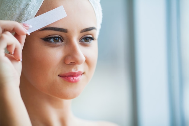 Cera para Remoção de Pêlos. Jovem mulher reciving depilação facial