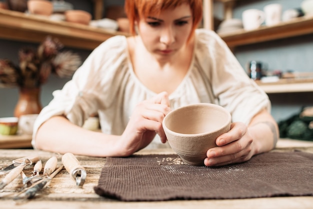 Cerâmica feminina decorando tigela de barro em estúdio