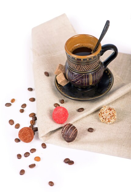 Cerámica negra antigua, granos de café, dulces y una taza de bebida