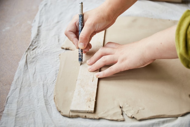 Ceramista feminina trabalhando no estúdio de cerâmica. Mãos Do Ceramist Sujas De Argila. Processo de criação de cerâmica. Mestre ceramista trabalha em seu estúdio