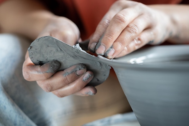 Ceramista usando costela de metal para moldar cerâmica oleiro trabalhando com argila na roda