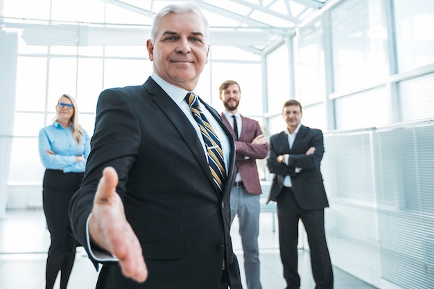 Foto de cerca. adulto empresario seguro tendiéndole la mano para un apretón de manos.