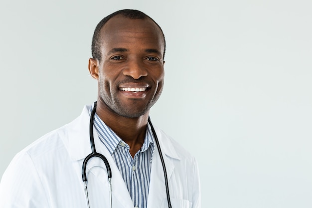 Cerca de alegre médico afroamericano sonriendo mientras está listo para trabajar