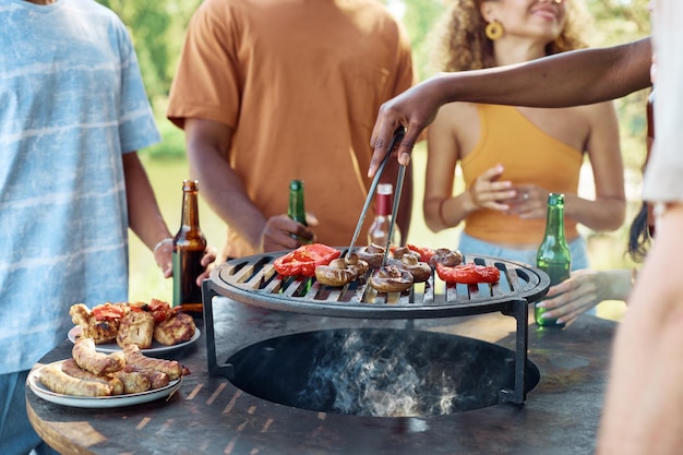 Cerca de amigos asando carne y verduras mientras disfruta de una fiesta de barbacoa al aire libre en verano