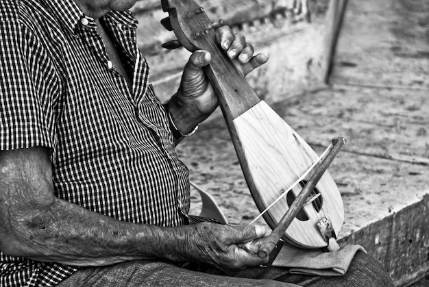 Foto cerca del anciano tocando algún instrumento tradicional