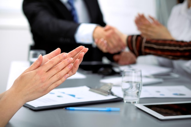 Cerca de aplausos femeninos mientras los empresarios se dan la mano en la reunión.