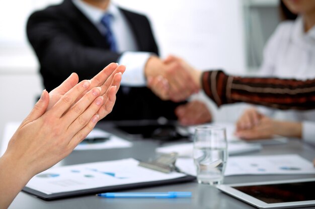 Cerca de aplausos femeninos mientras los empresarios se dan la mano en la reunión.