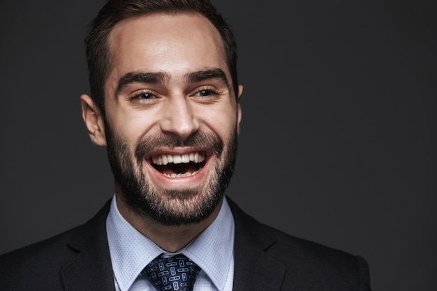 Cerca de un apuesto joven hombre de negocios sonriente vistiendo traje que se encuentran aisladas, mirando a otro lado