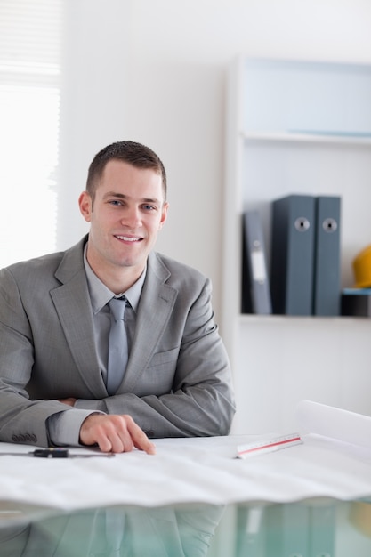 Cerca del arquitecto sonriente sentado detrás de una mesa