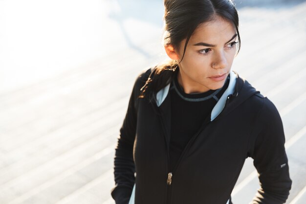 Foto cerca de una atractiva joven mujer fitness vistiendo ropa deportiva haciendo ejercicio al aire libre, posando